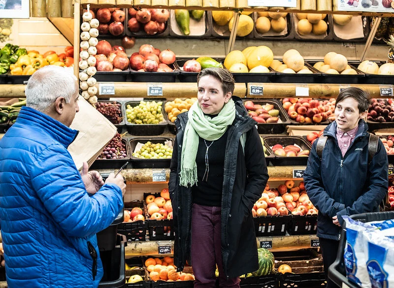 Carla Denyer of the Green Party listening intently to a shopkeeper in Bristol